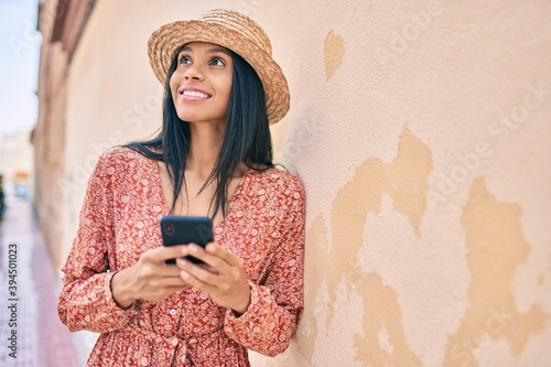 Young african american tourist woman on vacation smiling happy using smartphone at the city. © Krakenimages.com