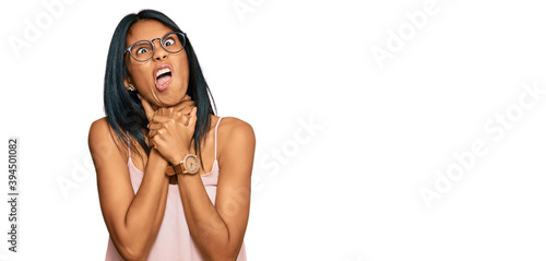 Young african american woman wearing casual clothes and glasses shouting suffocate because painful strangle. health problem. asphyxiate and suicide concept.