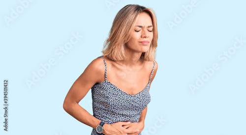 Beautiful caucasian woman wearing summer dress with hand on stomach because indigestion, painful illness feeling unwell. ache concept.