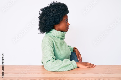 Young african american woman wearing casual winter sweater looking to side, relax profile pose with natural face with confident smile.
