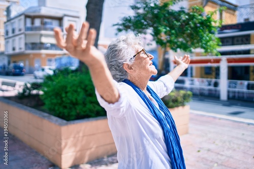 Bilde på lerret Elder senior woman with grey hair smiling happy with open arms sunbathing