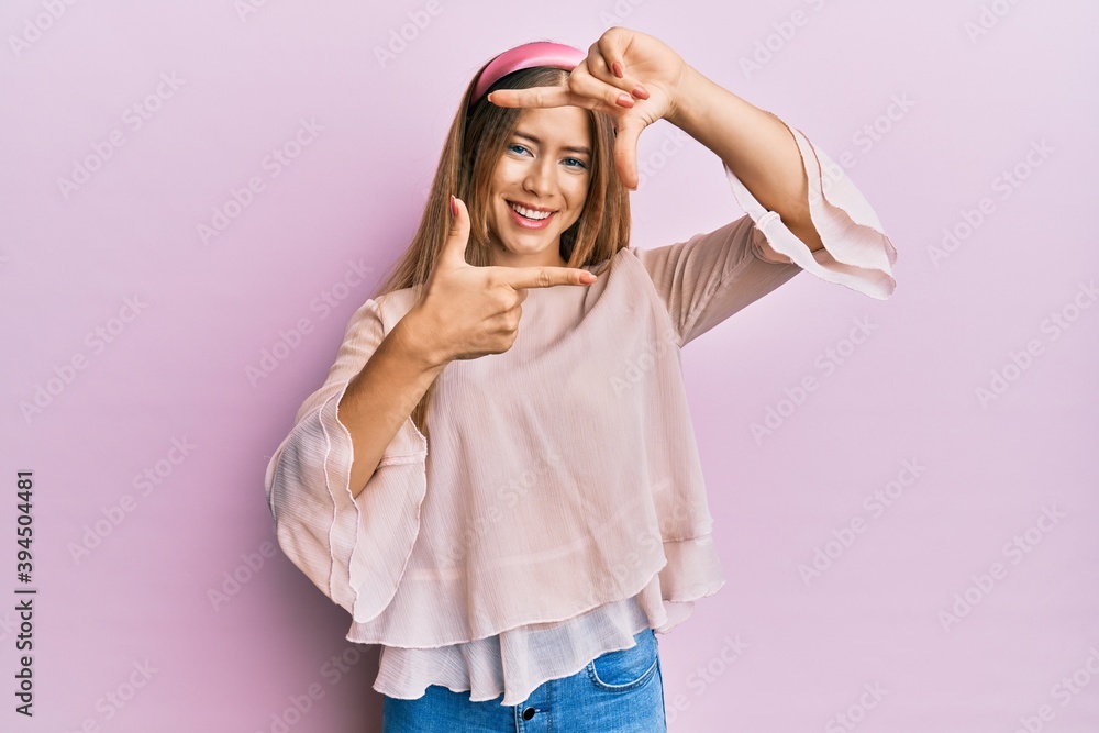 Beautiful young blonde woman wearing casual shirt and diadem smiling making frame with hands and fingers with happy face. creativity and photography concept. Beautiful young blonde woman wearing casual shirt and diadem smiling making frame with hands and fingers with happy face. creativity and photography concept.