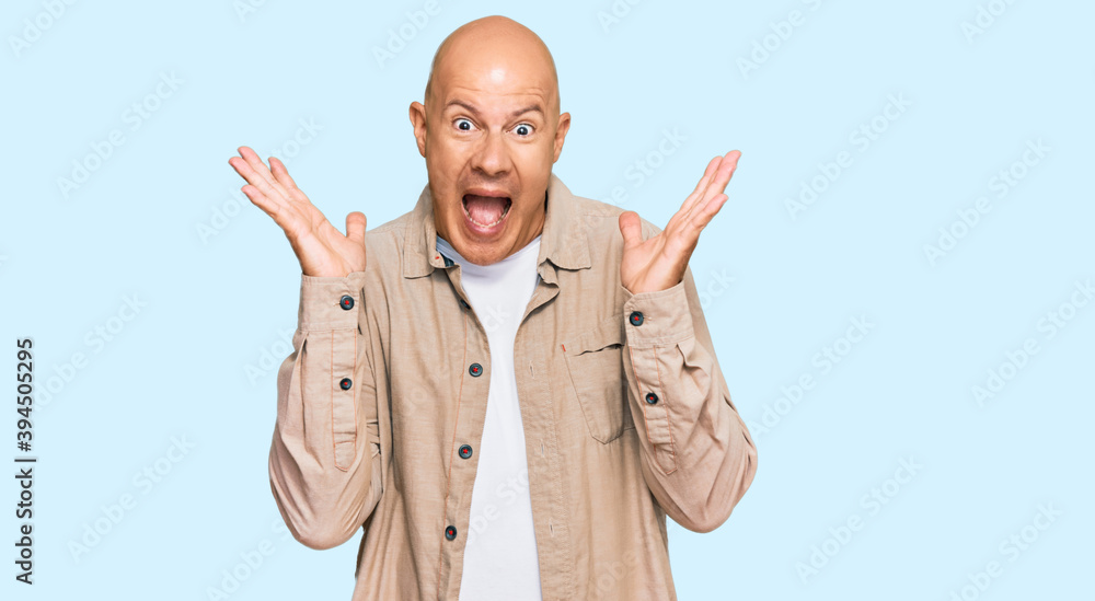 Middle age bald man wearing casual clothes celebrating crazy and amazed for success with arms raised and open eyes screaming excited. winner concept Middle age bald man wearing casual clothes celebrating crazy and amazed for success with arms raised and open eyes screaming excited. winner concept