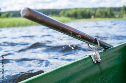 Metal oarlock holding an oar in a boat, against the background of a lake on a summer day. © koldunova