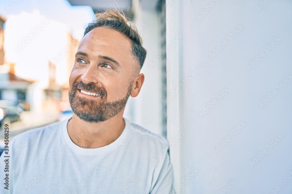 Middle age handsome man smiling happy leaning on the wall at the city. Middle age handsome man smiling happy leaning on the wall at the city.
