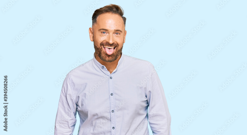 Handsome middle age man wearing business shirt sticking tongue out happy with funny expression. emotion concept. Handsome middle age man wearing business shirt sticking tongue out happy with funny expression. emotion concept.
