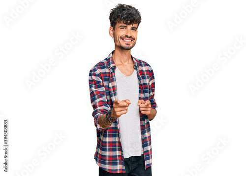 Young hispanic man wearing casual clothes pointing fingers to camera with happy and funny face. good energy and vibes.