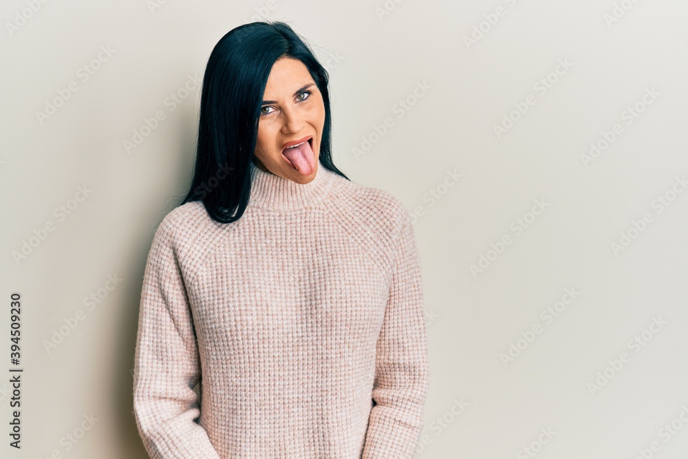 Fototapeta premium Young caucasian woman wearing casual winter sweater sticking tongue out happy with funny expression. emotion concept.