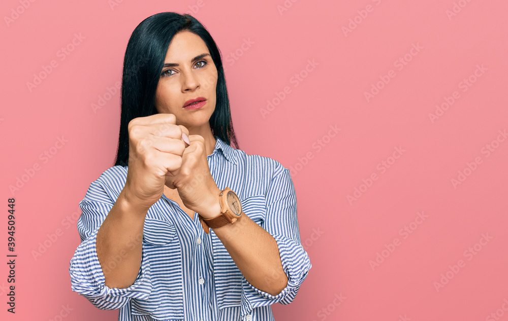 Young caucasian woman wearing casual clothes punching fist to fight, aggressive and angry attack, threat and violence Young caucasian woman wearing casual clothes punching fist to fight, aggressive and angry attack, threat and violence