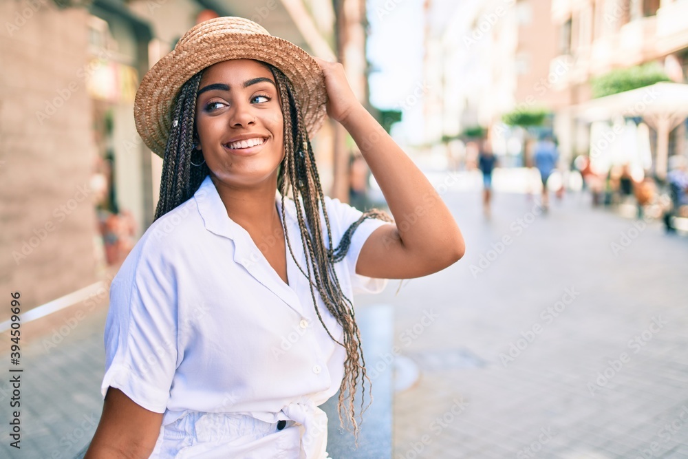 Young african american woman with braids smiling happy outdoors on a sunny day of summer