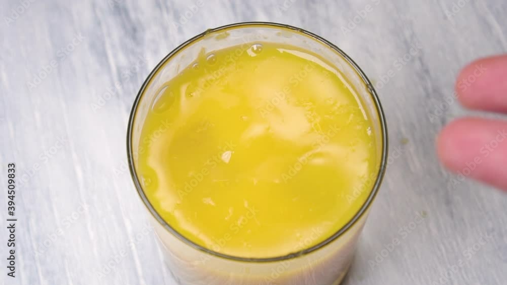 Slow Motion Shot of Ice Cubes Falling into Glass of freshly squeezed Orange Juice with pulp. On a wooden background Slow Motion Shot of Ice Cubes Falling into Glass of freshly squeezed Orange Juice with pulp. On a wooden background