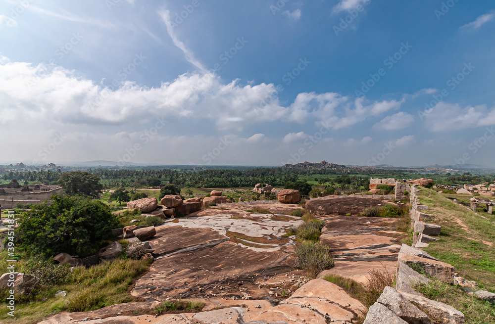 Hampi, Karnataka, India - November 4, 2013: Sunset Hill AKA Hemakatu. Ramparts ruins and boulders under blue cloudscape. 