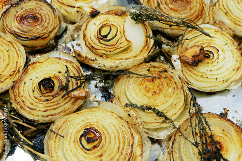 grilled caramalized half white onions with herbs on a metal tray photo