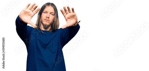 Handsome caucasian man with long hair wearing casual winter sweater doing frame using hands palms and fingers, camera perspective