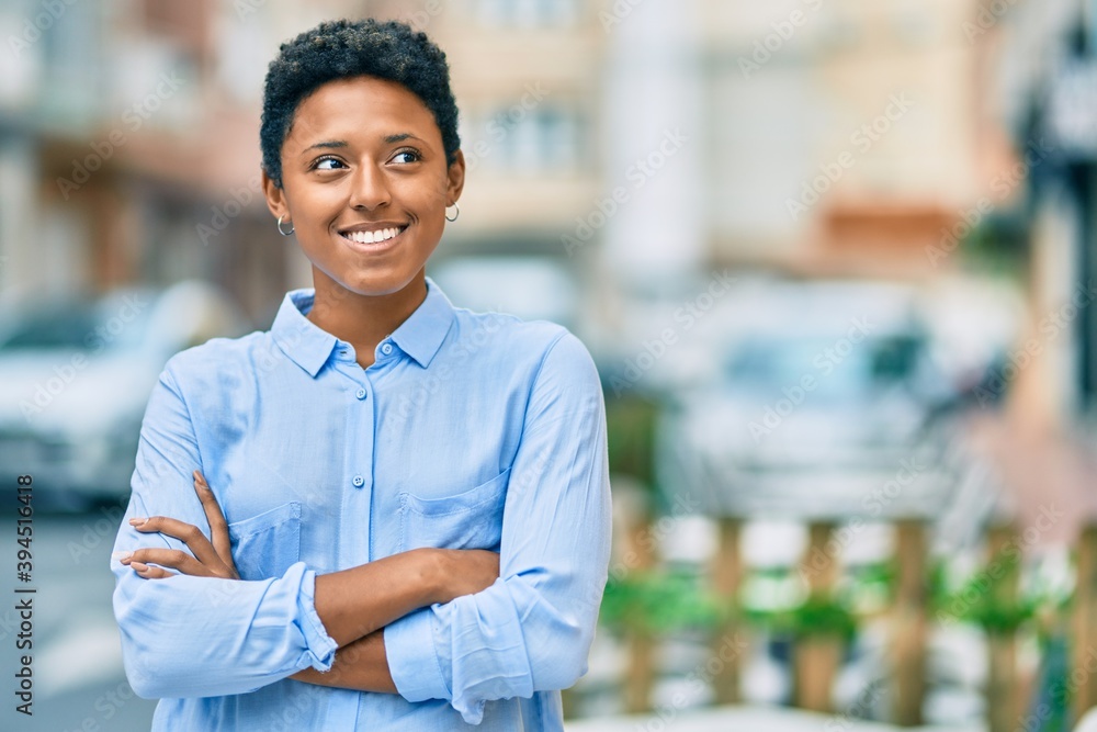 Fototapeta premium Young african american girl with crossed arms smiling happy at the city.