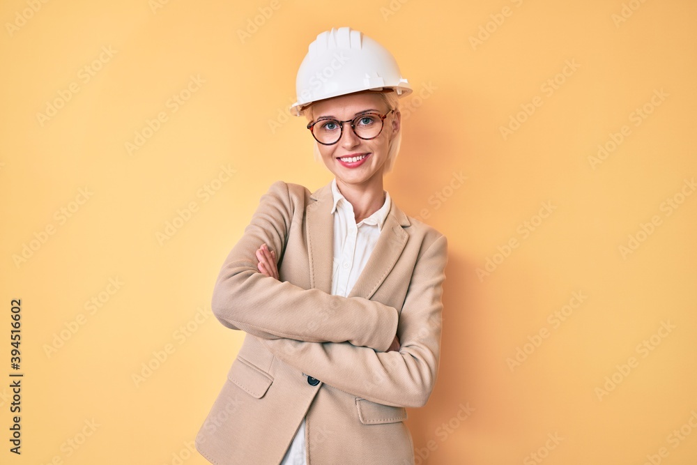 Young blonde woman wearing architect hardhat happy face smiling with crossed arms looking at the camera. positive person. Young blonde woman wearing architect hardhat happy face smiling with crossed arms looking at the camera. positive person.
