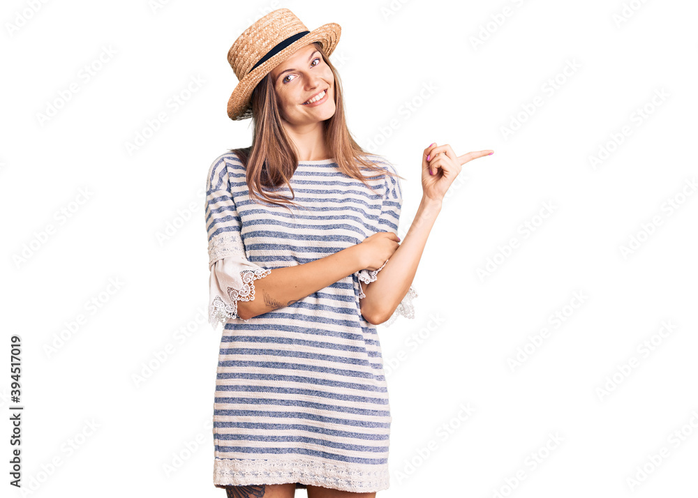 Beautiful caucasian woman wearing summer hat with a big smile on face, pointing with hand and finger to the side looking at the camera. Beautiful caucasian woman wearing summer hat with a big smile on face, pointing with hand and finger to the side looking at the camera.