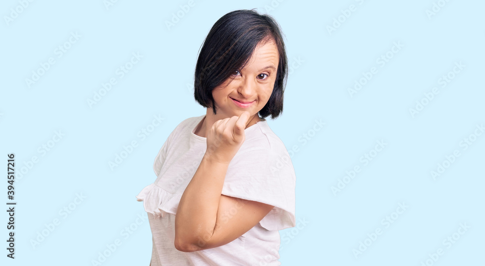 Brunette woman with down syndrome wearing casual white tshirt beckoning come here gesture with hand inviting welcoming happy and smiling Brunette woman with down syndrome wearing casual white tshirt beckoning come here gesture with hand inviting welcoming happy and smiling