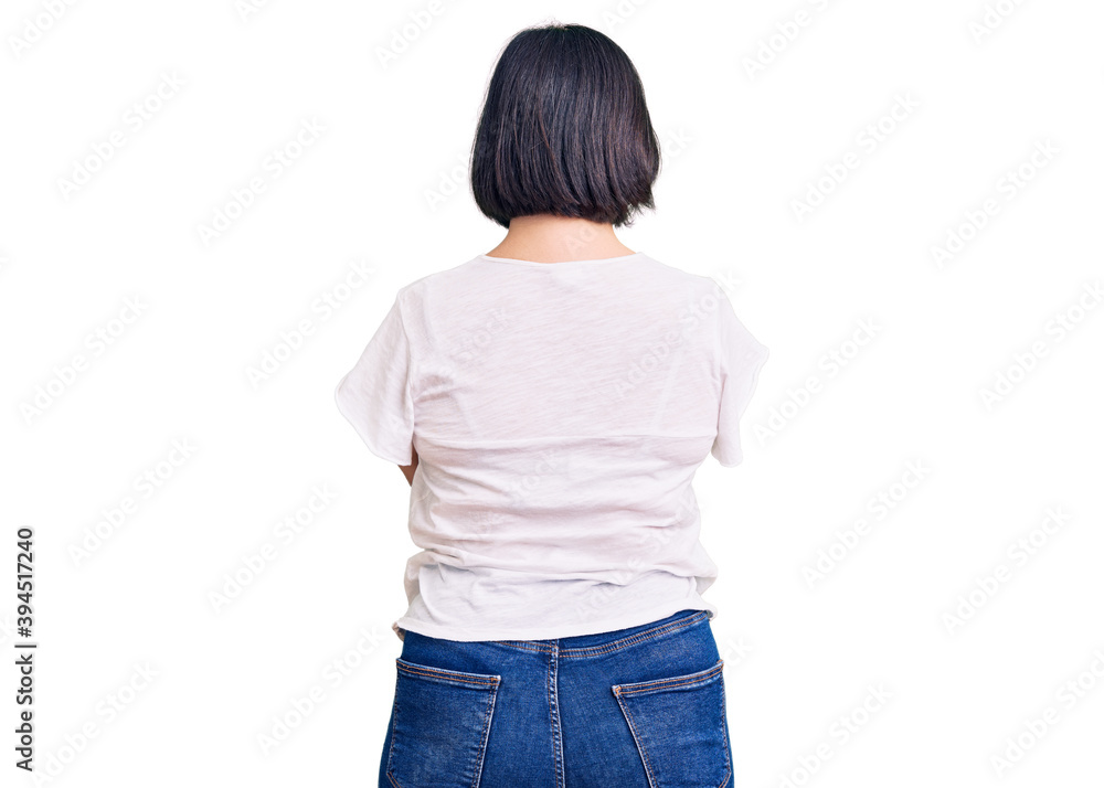 Brunette woman with down syndrome wearing casual white tshirt standing backwards looking away with crossed arms Brunette woman with down syndrome wearing casual white tshirt standing backwards looking away with crossed arms