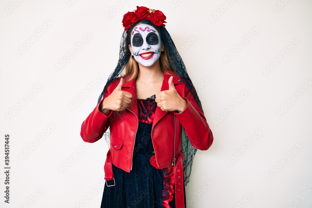 Woman wearing day of the dead costume over white success sign doing positive gesture with hand, thumbs up smiling and happy. cheerful expression and winner gesture. Woman wearing day of the dead costume over white success sign doing positive gesture with hand, thumbs up smiling and happy. cheerful expression and winner gesture.
