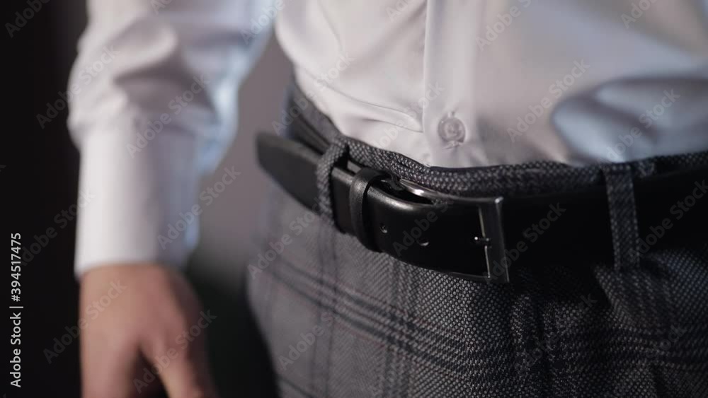 Groom wears a belt in slow motion. Man in white shirt puts belt on his pants in wedding morning. Businessman prepare to go to bride in wedding morning Groom wears a belt in slow motion. Man in white shirt puts belt on his pants in wedding morning. Businessman prepare to go to bride in wedding morning
