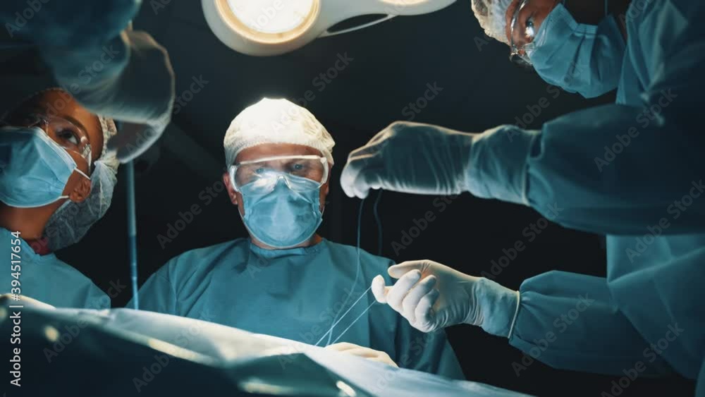Caucasian skillful surgeon with group of medical multi-race workers performing surgical operation in operating room of modern hospital. Caucasian skillful surgeon with group of medical multi-race workers performing surgical operation in operating room of modern hospital.