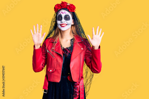 Woman wearing day of the dead costume over background showing and pointing up with fingers number ten while smiling confident and happy.