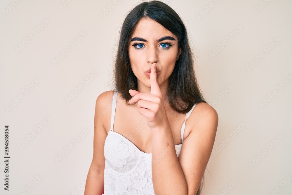 Brunette teenager girl posing elegant asking to be quiet with finger on lips. silence and secret concept. Brunette teenager girl posing elegant asking to be quiet with finger on lips. silence and secret concept.