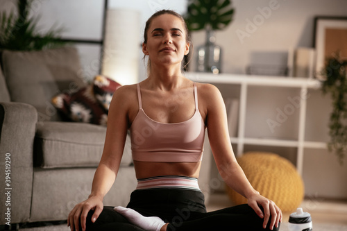 Athletic woman in sportswear doing fitness stretching exercises at home in the living room.