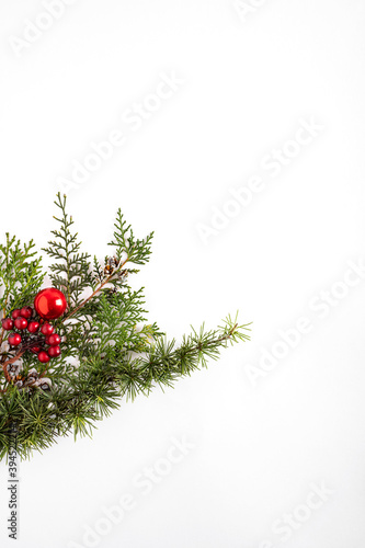  Creative winter layout made with evergreen tree branches and red round Christmas decorations. Flat lay.
