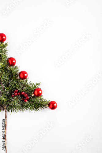 Creative Christmas tree concept. Creative winter layout made with evergreen tree branches and red round Christmas decorations. Flat lay.