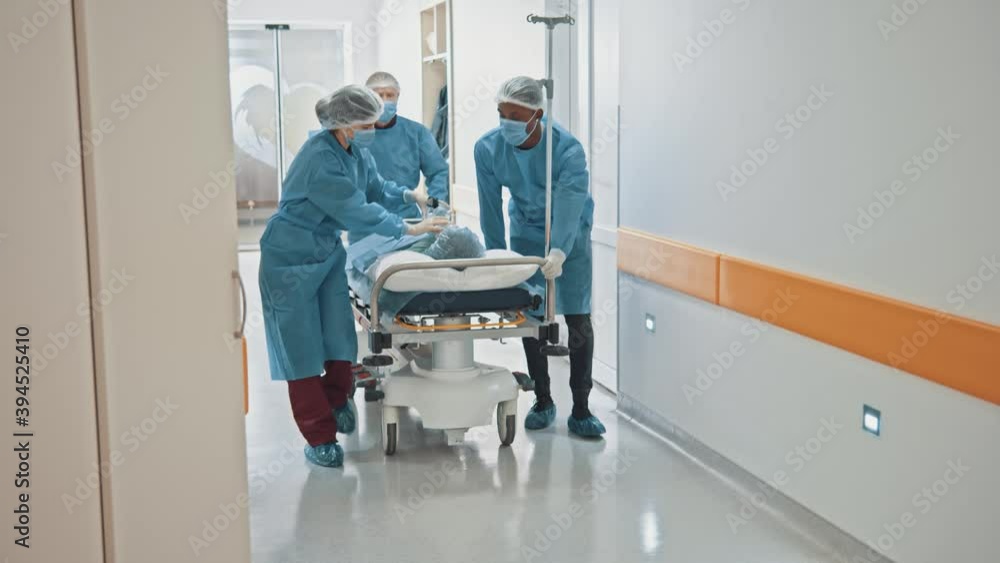 Cooperating multi-race team of paramedic doctors moving seriously injured male patient through hospital corridor. Emergency department. Cooperating multi-race team of paramedic doctors moving seriously injured male patient through hospital corridor. Emergency department.