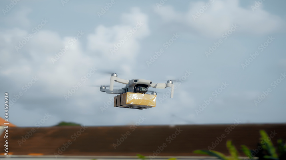 flying on a sky delivery drone with holding a .cardboard parcel flying on a sky delivery drone with holding a .cardboard parcel