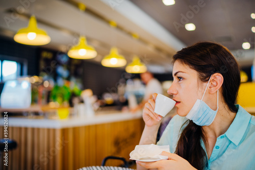 Fotografi Young woman in cafe public place wearing the protective face mask wrong way