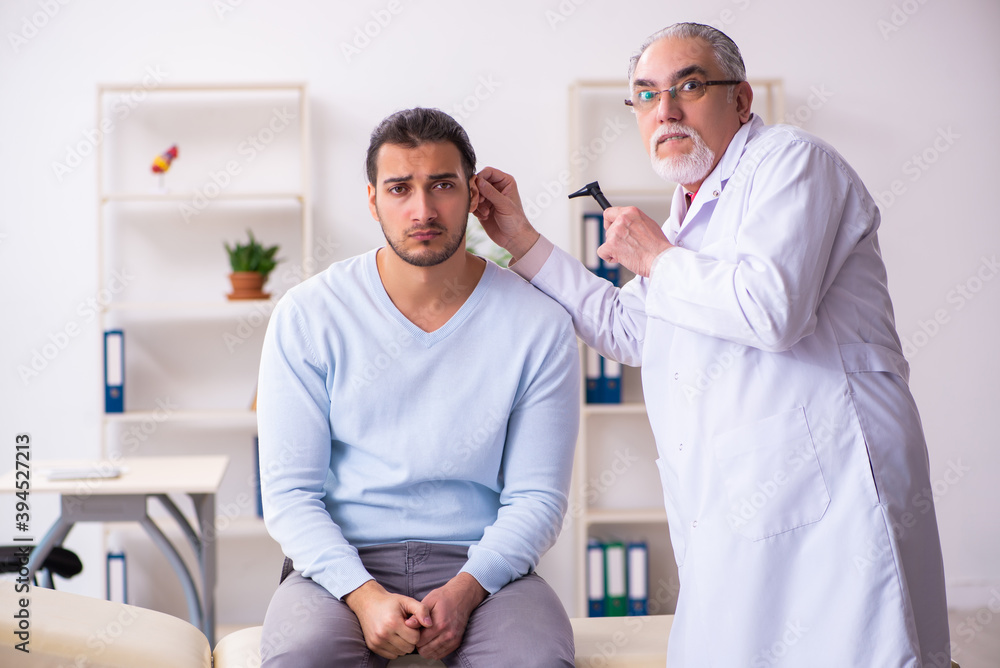 Young sick man visiting old doctor otolaryngologist Young sick man visiting old doctor otolaryngologist