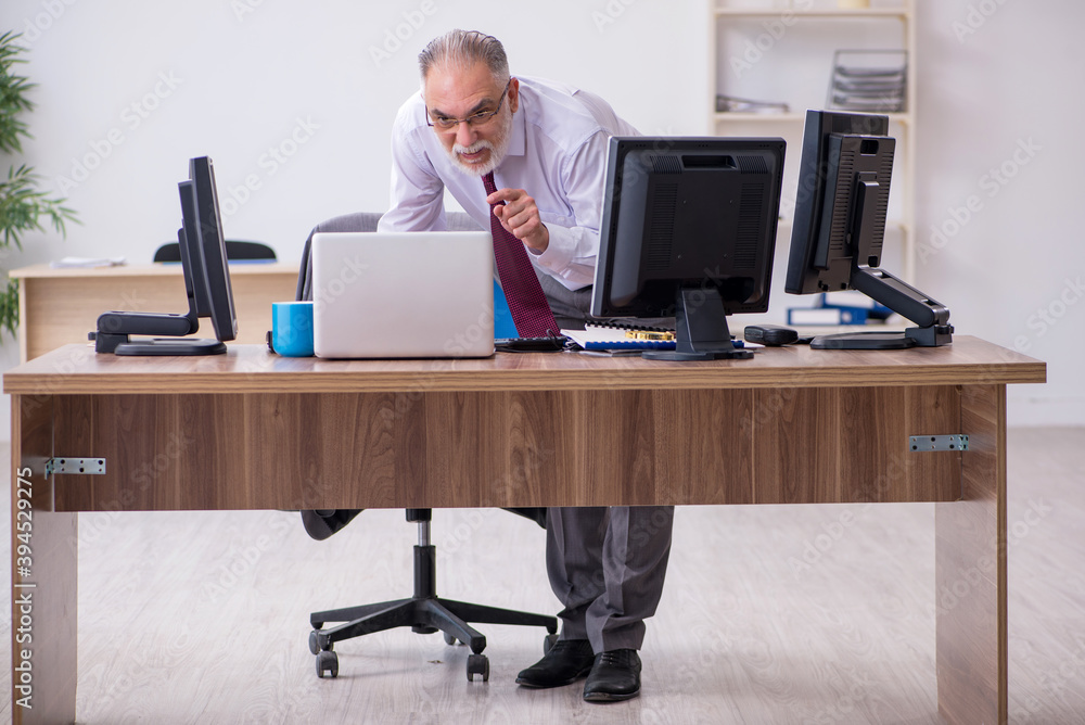 Old male boss sitting at desktop in the office Old male boss sitting at desktop in the office