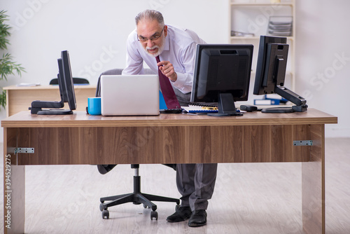 Old male boss sitting at desktop in the office