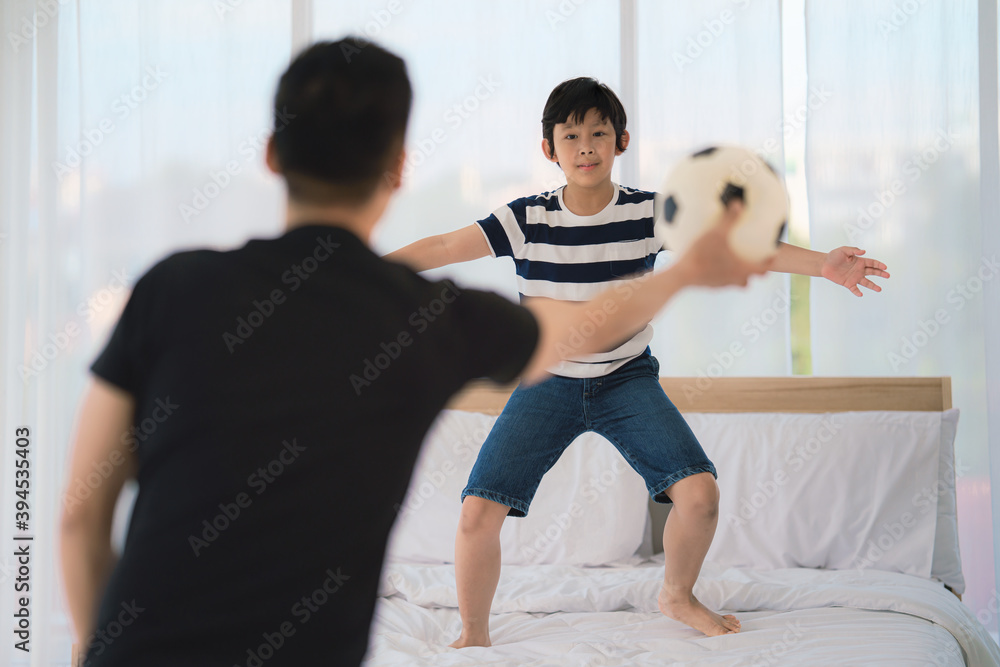 Fototapeta premium dad and son enjoy playing soccer football together in bedroom at home