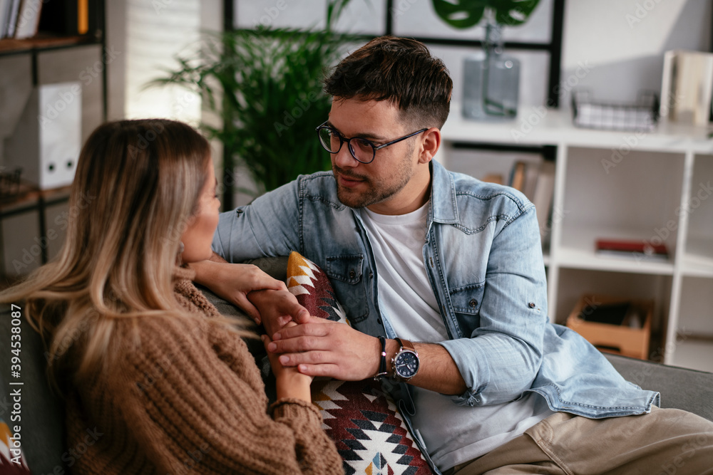 Fototapeta premium Young couple sitting and talking at home. Loving couple on a date.