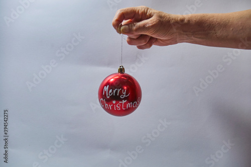 Hand holding a red christmas bulb, written Merry Christmas