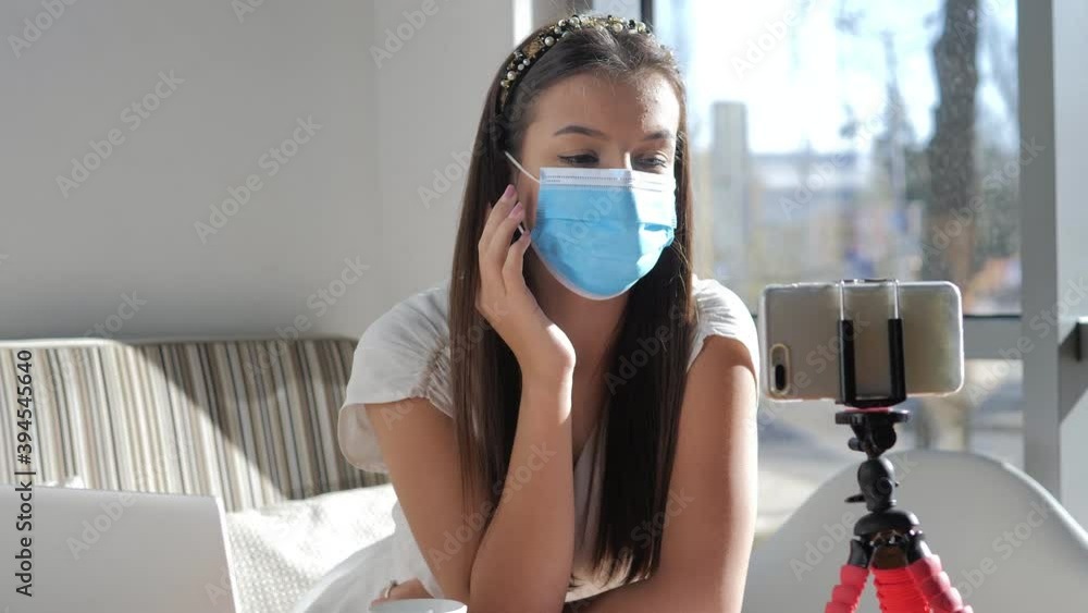 Distance learning concept. Young teenage girl wears protective medical mask, sits in office behind laptop and study online Distance learning concept. Young teenage girl wears protective medical mask, sits in office behind laptop and study online