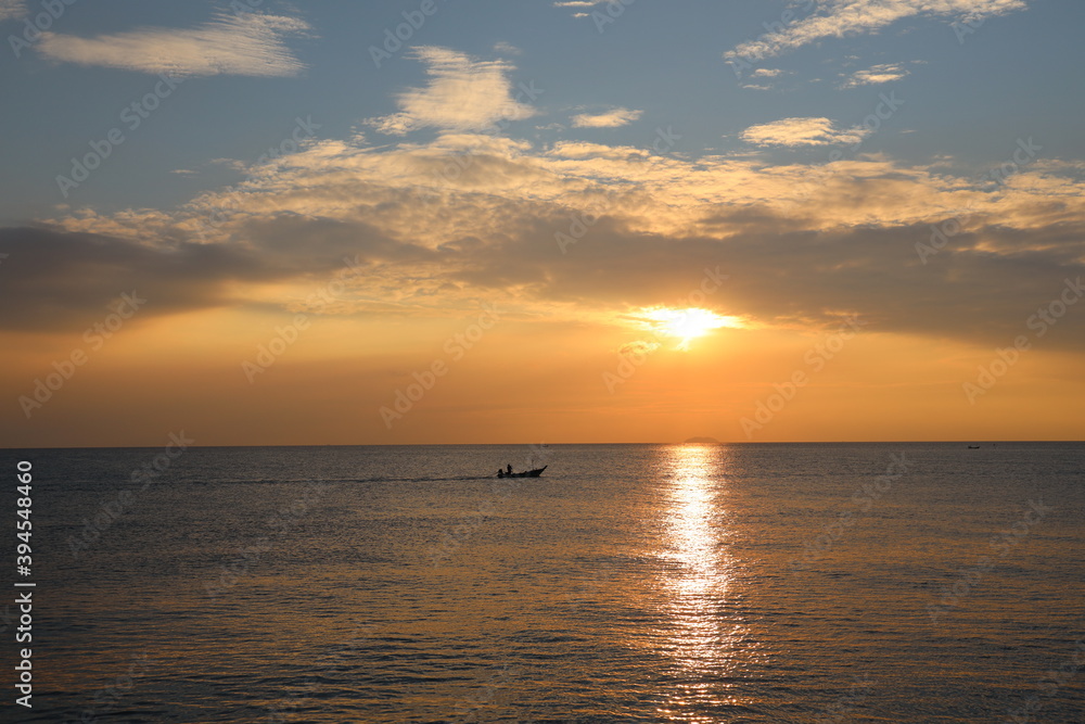Orange Sunset at dawn with the wide view of sea and small boat floating on the ocean Orange Sunset at dawn with the wide view of sea and small boat floating on the ocean