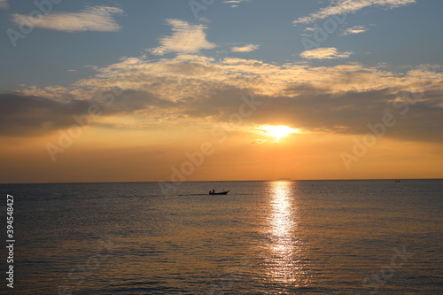 Orange Sunset at dawn with the wide view of sea and small boat floating on the ocean
