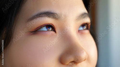 Close up, Eyes of happy young asian woman with pink eyeshadow looking through the window. High quality photo