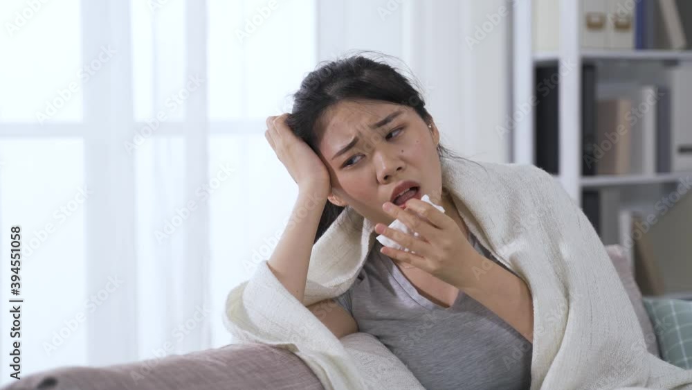 japanese lady catching virus disease wrapped up in blanket massaging temples is experiencing headache and persistent dry cough, and stay at home. japanese lady catching virus disease wrapped up in blanket massaging temples is experiencing headache and persistent dry cough, and stay at home.
