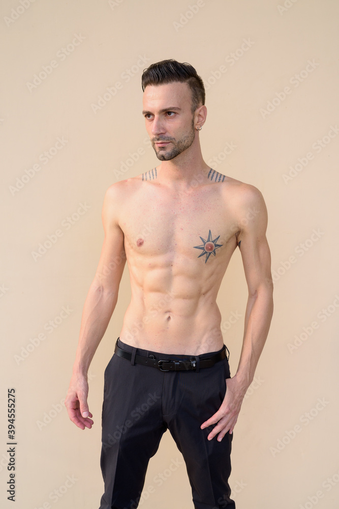 Portrait of handsome young man shirtless against wall Portrait of handsome young man shirtless against wall