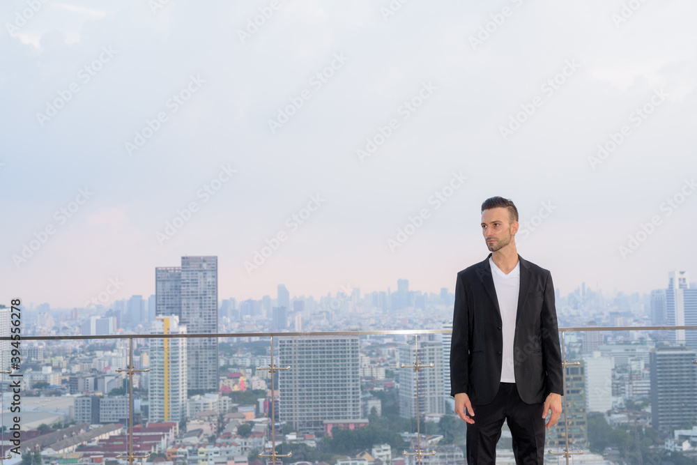 Portrait of businessman standing on the rooftop of a skyscraper with copyspace while thinking