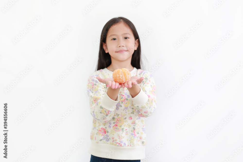 Portrait of little asian girl holding peeled orange fruit on white background. Focus at orange in hands Portrait of little asian girl holding peeled orange fruit on white background. Focus at orange in hands