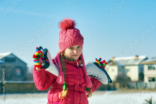 Portrait of a girl with skates on the street on a winter day