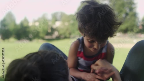 A son laughs and smiles while playing with his mother on a sunny day at the park